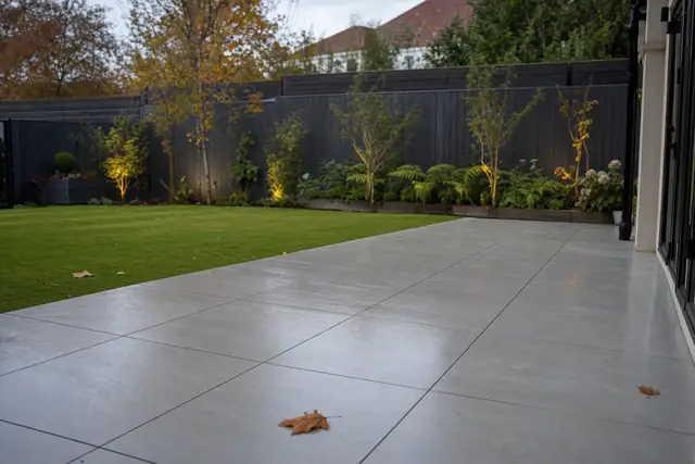 Large-format light grey porcelain patio with thin joints beside a neat lawn in a Cardiff back garden.